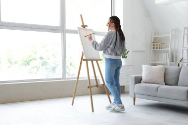 Evde sehpaya resim çizen rastalı genç bir kadın.