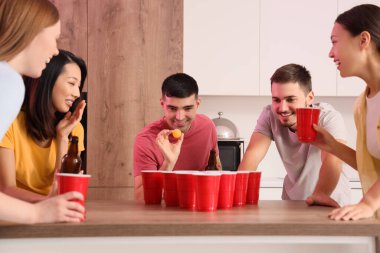 Bir grup genç arkadaş partide bira pong oynuyorlar.