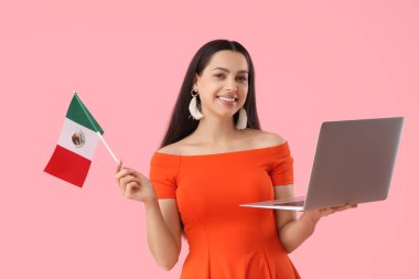 Pembe arka planda Meksika bayrağı ve laptopu olan genç bir kadın.