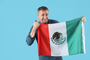 Mavi arka planda Meksika bayrağı olan olgun bir adam.
