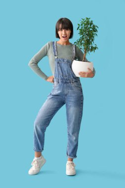 Mavi arka planda bitkileri olan genç ve güzel bir bahçıvan.