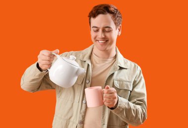 Turuncu arka plana çay döken genç adam.