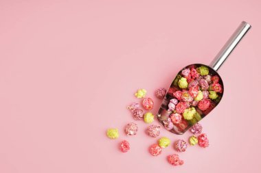 Pembe arka planda tatlı patlamış mısırlı metal kepçesi