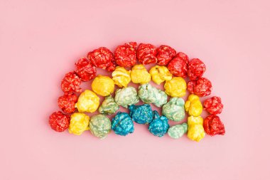 Pembe arka planda patlamış mısırdan yapılmış gökkuşağı