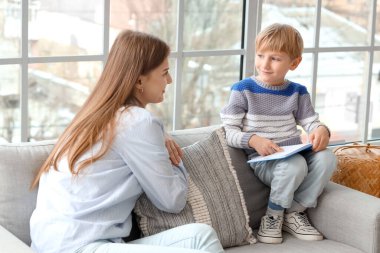 Anne ve oğlu evdeki kanepede kitap okuyorlar.