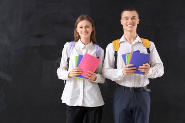 Kitapları ve sırt çantaları karatahta üzerinde olan öğrenciler. Okul kavramının sonu