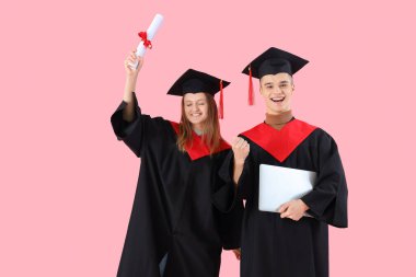 Diplomalı ve pembe arka planda dizüstü bilgisayarı olan yüksek lisans öğrencileri. Okul kavramının sonu