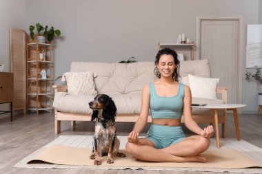 Cocker spanyel ile evde meditasyon yapan Afro-Amerikalı genç bir kadın.