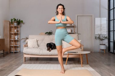 Cocker Spaniel 'le evde yoga yapan Afro-Amerikan bir kadın.