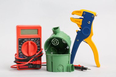 Işık arka planında çoklu metre, plastik soket kutuları ve tel sökücü.