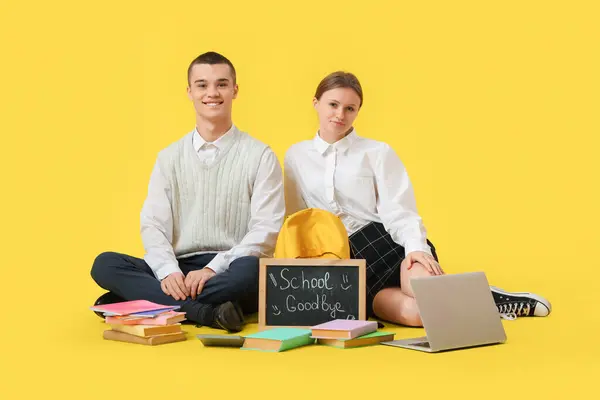 Students with books, laptop and chalkboard with text GOODBYE SCHOOL on yellow background. End of school concept