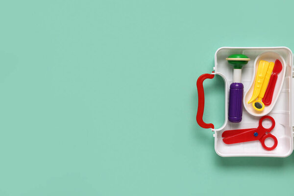 Open toy first aid kit on turquoise background. Top view
