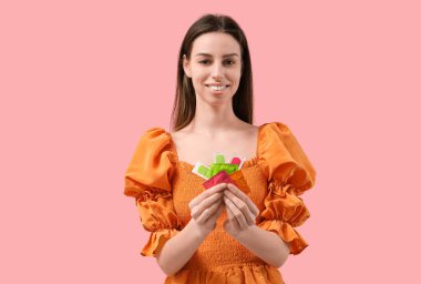 Pembe arka planda farklı doğum kontrol yöntemleri olan güzel bir genç kadın.