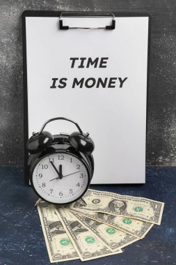 Siyah grunge arka planına karşılık üzerinde Time mesajı olan pano para, alarm saati ve dolar banknotlarıdır