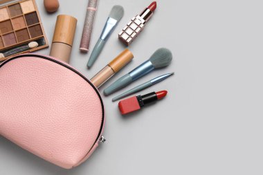 Gri arka planda çantalı dekoratif kozmetik seti. Üst görünüm