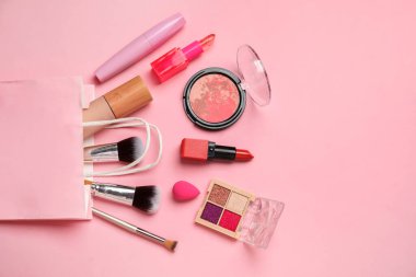 Pembe arka planda alışveriş poşetinde kozmetik ürünler. Üst görünüm