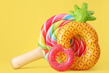 Yüzen yatak ve sarı arka planda farklı şekillerde şişme halkalar.