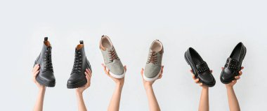 Hafif arka planda farklı şık ayakkabıları olan kadın elleri.