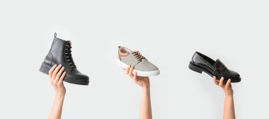 Hafif arka planda farklı şık ayakkabıları olan kadın elleri.