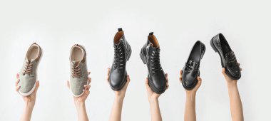 Hafif arka planda farklı şık ayakkabıları olan kadın elleri.