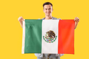 Sarı arka planda Meksika bayrağı olan yakışıklı bir adam.