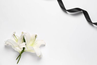 Beyaz arka planda siyah cenaze kurdelesi olan güzel zambak çiçeklerinden yapılmış çerçeve.