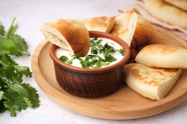 Beyaz arka planda lezzetli pita ekmeği ve soslu tabak.