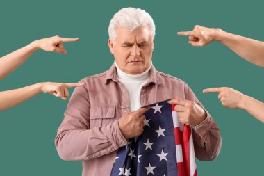 People pointing at mature man with USA flag on green background. Accusation concept clipart