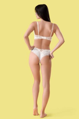 Sarı arka planda beyaz dantelli iç çamaşırlı güzel bir kadın.