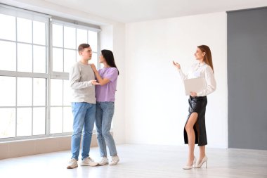 Dizüstü bilgisayarı olan emlakçı genç çifte yeni evi gösteriyor.