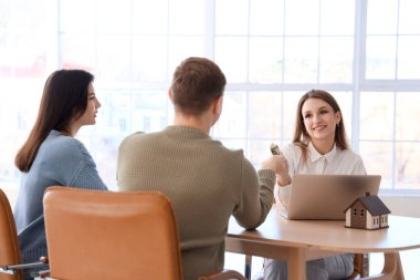 Emlakçı ofisteki çiftten ev için ödeme alıyor.