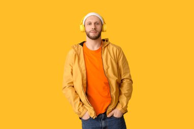 Sarı arka planda modern kulaklıklı genç adam.