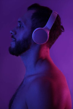 Mor arka planda modern kulaklıklı genç adam.