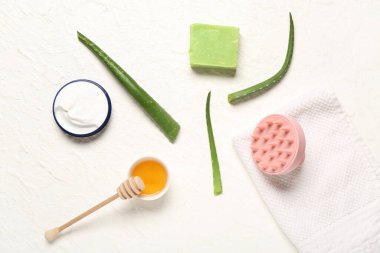 Saç derisi masaj aleti, şampuan barı, aloe vera, beyaz arka planda bal ve krema.