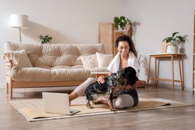 Sportif, Afro-Amerikalı, cocker spaniel köpeği olan genç bir kadın evde antrenmandan sonra oturuyor.