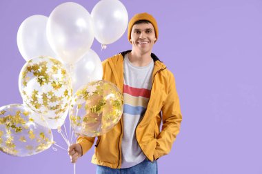 Leylak arka planında balonlar olan günlük kıyafetli genç bir adam.