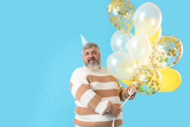 Mavi arka planda balonları olan son sınıf öğrencisi.