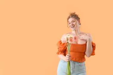 Sarı arka planda güzel Gerbera çiçekleri olan mutlu genç bir kadın.