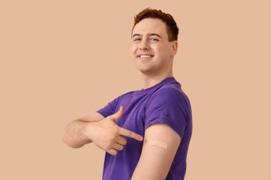 Bej arka planda uygulamalı tıbbi yaması olan mutlu genç bir adam. Aşılama kavramı