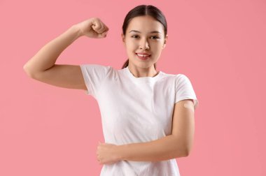 Pembe arka planda uygulamalı tıbbi yaması olan güzel bir genç kadın.