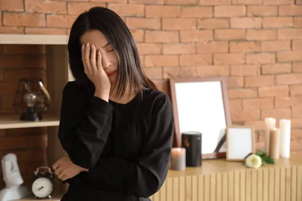 Grieving young Asian woman crying at funeral
