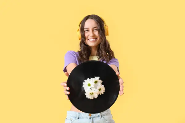 Młoda Kobieta Słuchawkach Trzyma Dysk Winylowy Wiosennymi Kwiatami Żółtym Tle — Zdjęcie stockowe