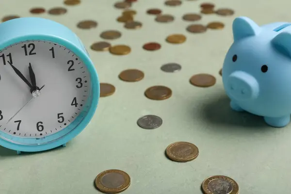 Composition with piggy bank and alarm clock on green background. Time management concept