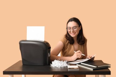 Sekreterin bej arkaplandaki belgeyi parçalayıcı ile yok etmesi