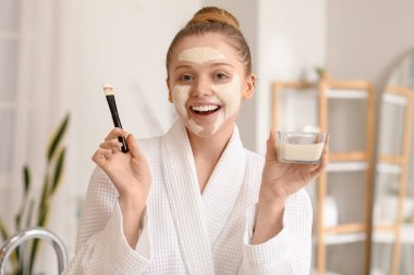 Zerdeçal maskeli ve banyoda fırça kullanan genç bir kadın.