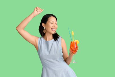 Yeşil arka planda bir bardak lezzetli aperol spreyli güzel Asyalı kadın.