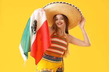 Sarı arka planda Meksika bayrağı olan şapkalı genç bir kadın.