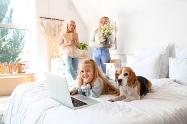 Küçük şirin kız ve köpek yatak odasında çizgi film izliyorlar.