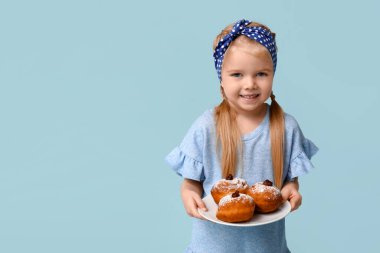 Mavi arka planda lezzetli donutları olan tatlı, mutlu, küçük bir kız. Hanuka kutlaması