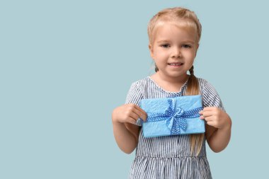 Mavi arka planda hediye kutusu olan şirin, mutlu küçük bir kız. Hanuka kutlaması